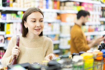 Fototapeta premium Woman buyers chooses shampoo or shower gel in household chemicals store