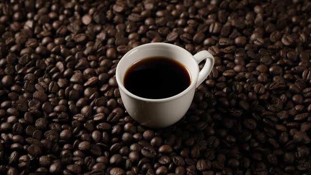 Cinematic video of a small espresso cup placed on a textured surface made entirely of roasted coffee beans