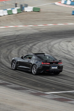 Black Chevrolet Camaro SS rear view panning shot, V8 muscle car driving fast through track corner