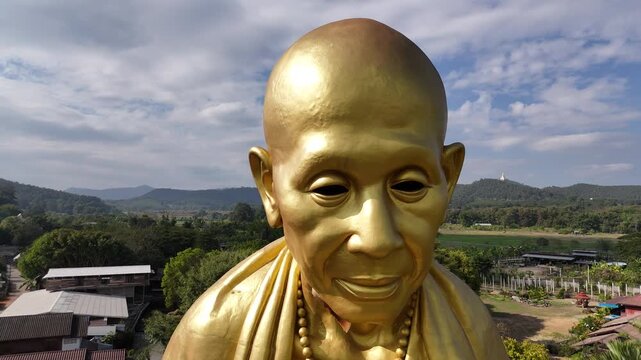 Detailed drone orbit of massive monk sculpture, showcasing intricate facial features