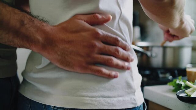 Man stirring saucepan at stove after starting meal prep, partner placing hand, sharing cooking care