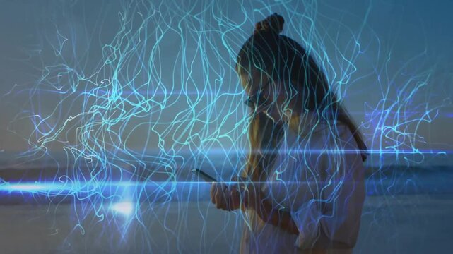 Woman standing on beach at twilight previewing AR while tapping smartphone activating blue streaks