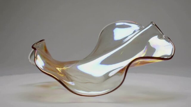 Iridescent sheet rotating, morphing above table, frames driving rotation, showing glints for design