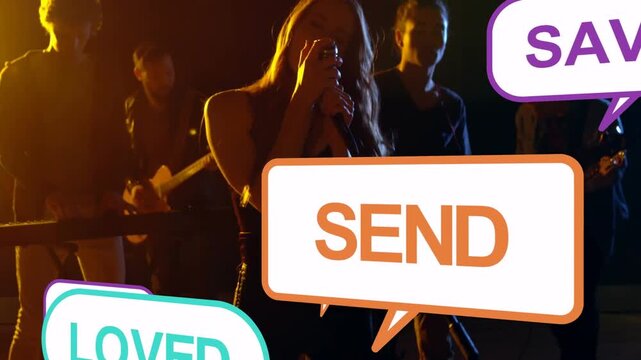 Singing singer into mic on dim amber-lit stage in dark top with floating callouts and guitars