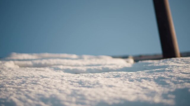 Closeup snow texture on home roof. Lowangle study of grainy snow surface with rusted pipe edge, shallow depth of field and soft bokeh sky, gentle morning light, melting granules and tactile detail,