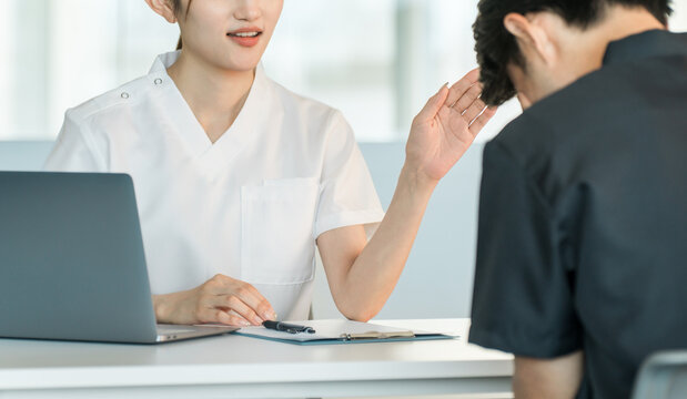 A female staff member in a white coat comforts a male patient during a counseling session.