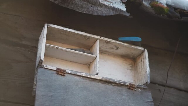 Rustic wooden spice box lies empty on counter, home cook inspects worn compartments in warm morning light, faded paint and peeling finish, ceramic cup at edge, intimate domestic scene of preparing