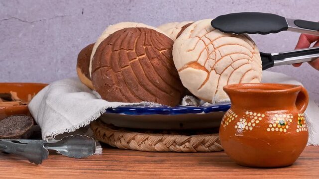 Hand places a vanilla concha bread on a plate using silicone tweezers