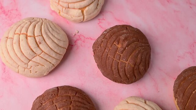 Top view of traditional Mexican conchas on a pink marble surface