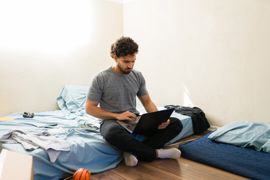 College student struggling with new independent life, making ends meet in first apartment, sitting on floor working with laptop