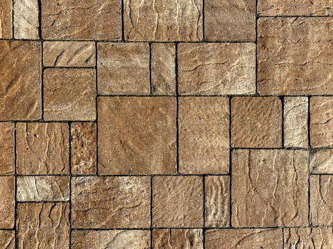 Interlocking tan bricks form a textured surface with visible grain and sand between the joints creating a durable pattern suitable for a patio walkway or outdoor flooring