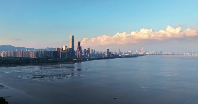 Aerial view of Shenzhen coastal city skyline with modern skyscrapers and sea at sunset, Guangdong, China.