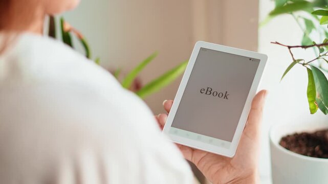Person holding ebook reader at home near plants. Digital reading, modern lifestyle, education and relaxation concept with portable device and minimal cozy interior. Dozens suggestions with easy search