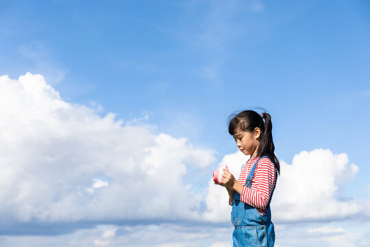 A little Chinese girl playing with a bubble machine outdoors