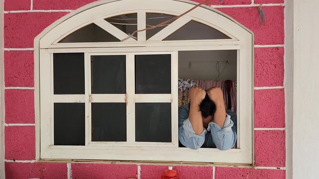 Anxious Man Hiding Face in Hands by the Window