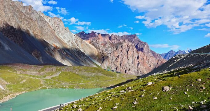 Pristine alpine turquoise lake surrounded by rugged mountains under a clear blue sky in Xinjiang, China.