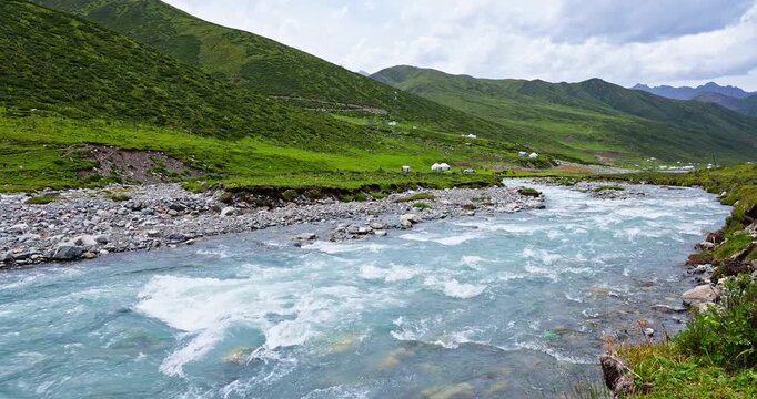 Fast-flowing mountain river with crystal-clear water rushing over rocks in a mountain valley, Xinjiang, China.