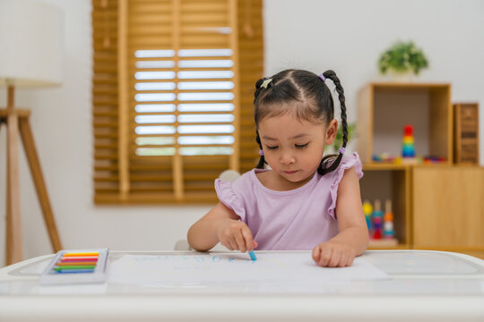 preschool child girl drawing and painting with colorful oil pastels on paper