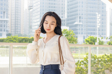 Fototapeta premium A portrait of an Eastern businesswoman, an urban white-collar worker, using her mobile phone