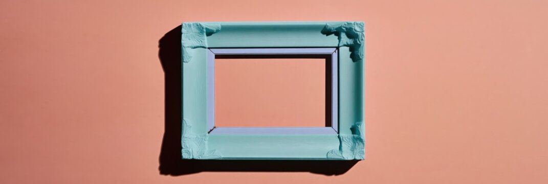 Antique icy blue picture frame with ornate floral carvings on a peach surface for elegant interior design mockup with copy space and dramatic shadow detail