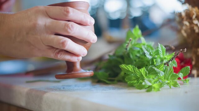 Home cook hands preparing fresh herbs on board beside ceramic cup, bright window light, mint sprigs and texture focus, careful arranging for garnish or infusion, lively kitchen garden vibe