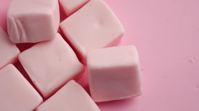 Pink square chewing gum candy rotating on pink background delicious sweet sugary treat.