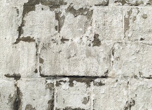 Light gray, almost white cinder block wall covered with lime chalk water-based paint. Old rustic stone surface texture. Close-up.