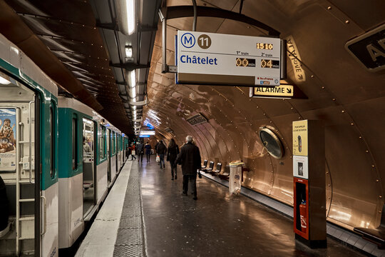Busy underground metro station platform with train signs and commuters in Paris