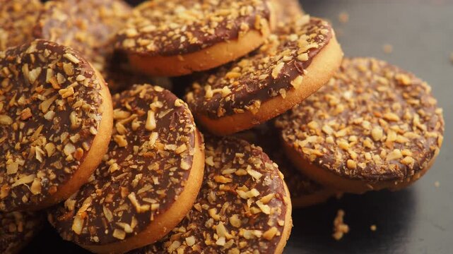 Delicious chocolate cookies with nuts in pile slow motion.