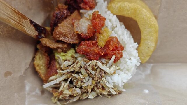 Traditional Indonesian Nasi Bungkus with rice, sambal, and side dishes in brown paper