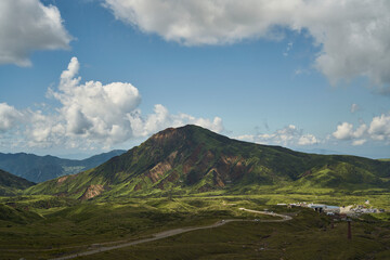 Fototapeta premium Vast volcanic landscape with green mountains, crater terrain and dramatic summer clouds
