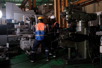 Fototapeta premium Workers use machinery in a workshop during the day while wearing safety gear and focused on their tasks