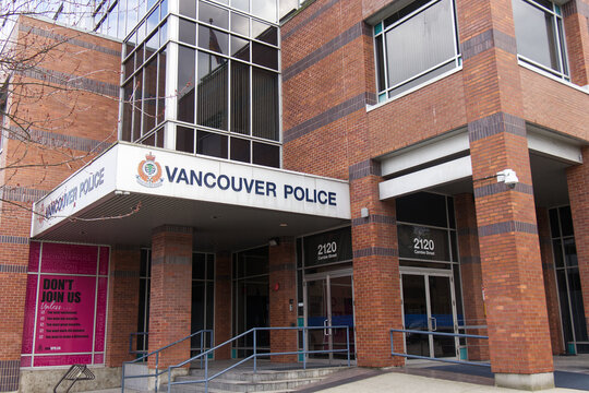 Vancouver Police headquarters building at 2120 Cambie Street with departmental sign, crest, and pink recruitment poster on brick facade