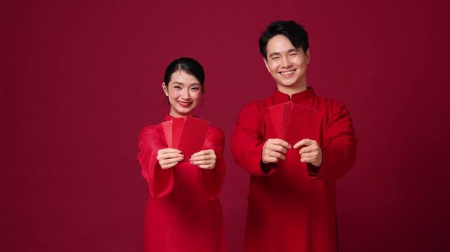 Asian couple holding red envelopes together, smiling, classic Lunar New Year greeting concept