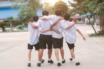 Fototapeta premium Four High School Friends Walking with Arms on Shoulders on Campus.Concept of best friends