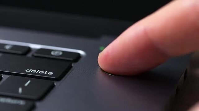 Finger pressing delete laptop keyboard button.