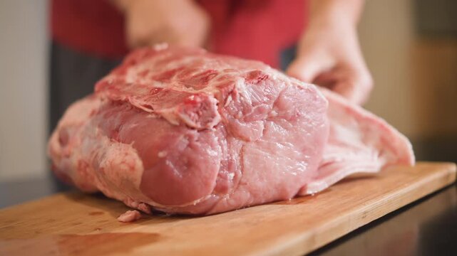 Home cook trimming raw pork roast on wooden board, closeup knife removing outer fat and membrane, warm kitchen light, hands in apron, seasoning and tenderizing for family dinner roast, rustic comfort