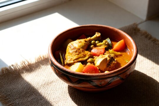 Spicy Yassa Chicken Stew in Rustic Bowl with Sunlight