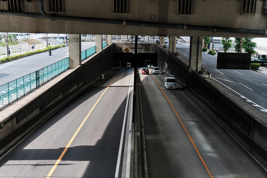 Sunlit underpass roadway receding beneath layered urban infrastructure