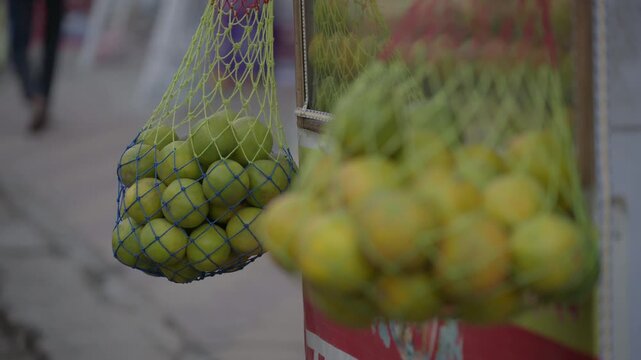 Close up of ripe citrus fruits displayed in traditional net bags at a local market. Ideal for travel, food industry, and healthy lifestyle content.