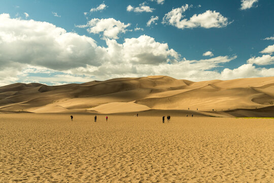 USA, Colorado, Great Sand Dune National Park.  Lots of park visitors walking towards the dunes.   The dunes cover an area of about 30 sq mi (78 km2)