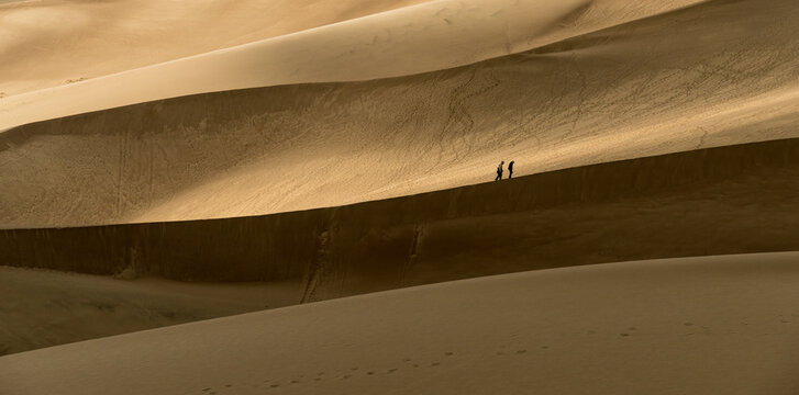 USA, Colorado, Great Sand Dune National Park.  A couple walking on the edge of a dune.   The dunes cover an area of about 30 sq mi (78 km2)