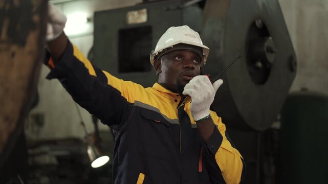 Professional industrial engineer communicating with walkie talkie during factory inspection
