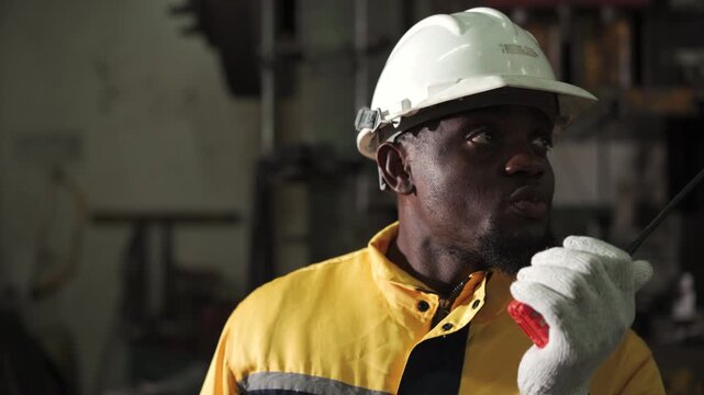 Professional industrial engineer communicating with walkie talkie during factory inspection
