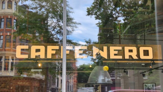 London UK 02.07.2025 caff&egrave; nero cafe sign on glass window with city reflections trees and buildings urban coffee shop exterior branding and lifestyle concept
