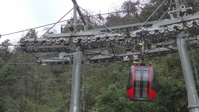 Red Gondola Lift (Cable Car) arriving at mountain station with overhead cable system and forest background