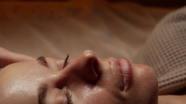 Close-up relaxing facial massage with gentle hand touch on serene woman face, highlighting soothing skincare ritual, glowing complexion, and peaceful spa atmosphere