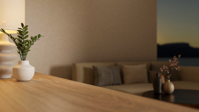 Close up a potted plant on wooden counter table across sofa couch and wall window in dim living room
