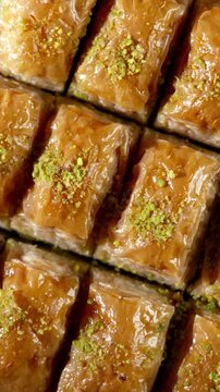 Top view slow motion of baklava dessert pieces rotating. Traditional Middle Eastern pastry with pistachio topping, glossy syrup and rich layered texture.