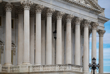 Fototapeta premium Columns stone architectural perspective symmetry. Columns marble fluted repetition. Columns decorative capitals carved detail. Columns classical facade.
